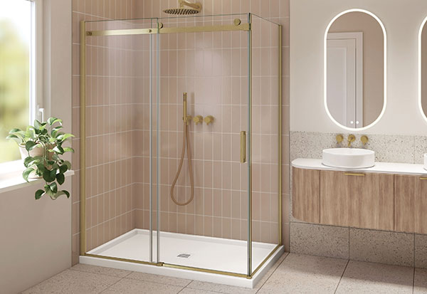 Une salle de bains de rêve avec des tuiles roses dans la douche, des accents dorés brossés et une vanité en bois clair avec un miroir DEL oblongue