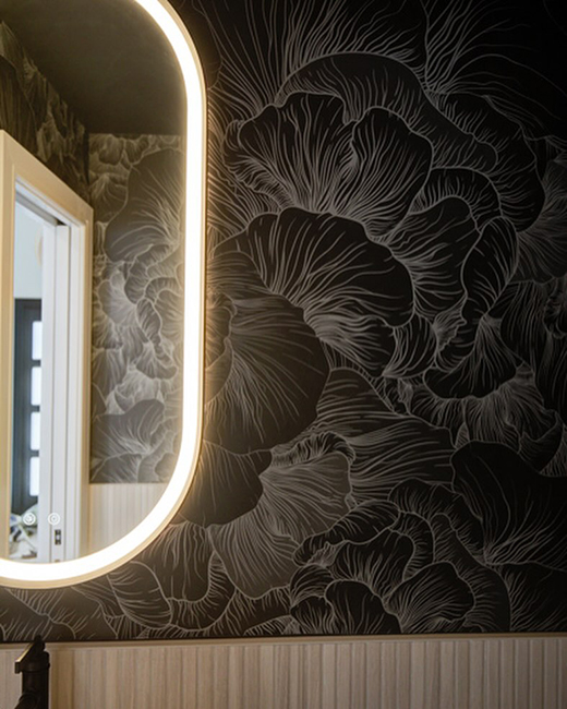 fleurco's magna brushed gold oblong framed mirror installed on a dark flower patterened accent wall