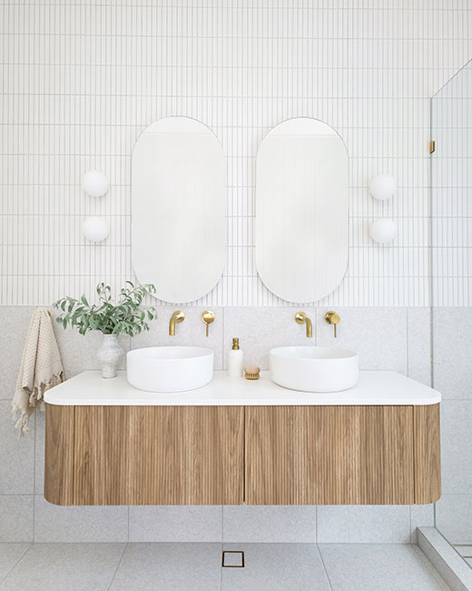 Vanité double flottante en bois décorée de 2 miroirs oblongs dans une salle de bain blanche évoquant une ambiance calme.