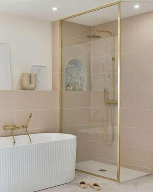 A white bathroom with pink hues featuring a bathtub & a walk-in shower with a brushed gold frame