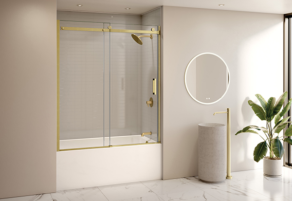 Fleurco's brushed gold Horizon tub door in a light beige bathroom, with soft natural materials like marble floor tiles & stone basin