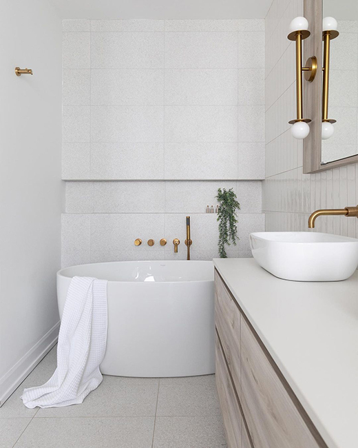 a soft white bathroom design with natural textures like soft beige wood tones, light terazzo tiles, and an acrylic white glossy bathtub